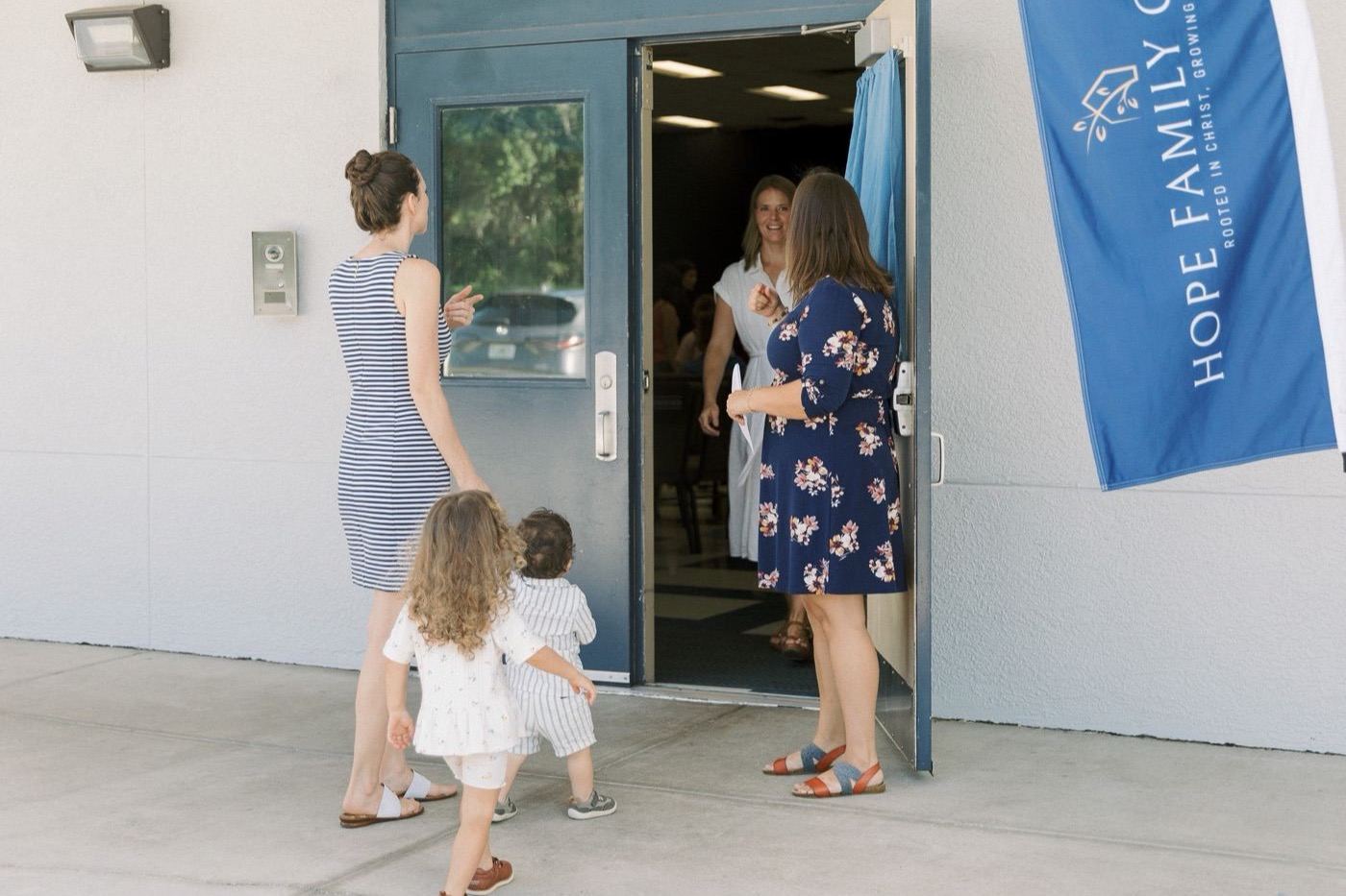 Family being greeted at the entrance of Hope Family Church with welcome banner