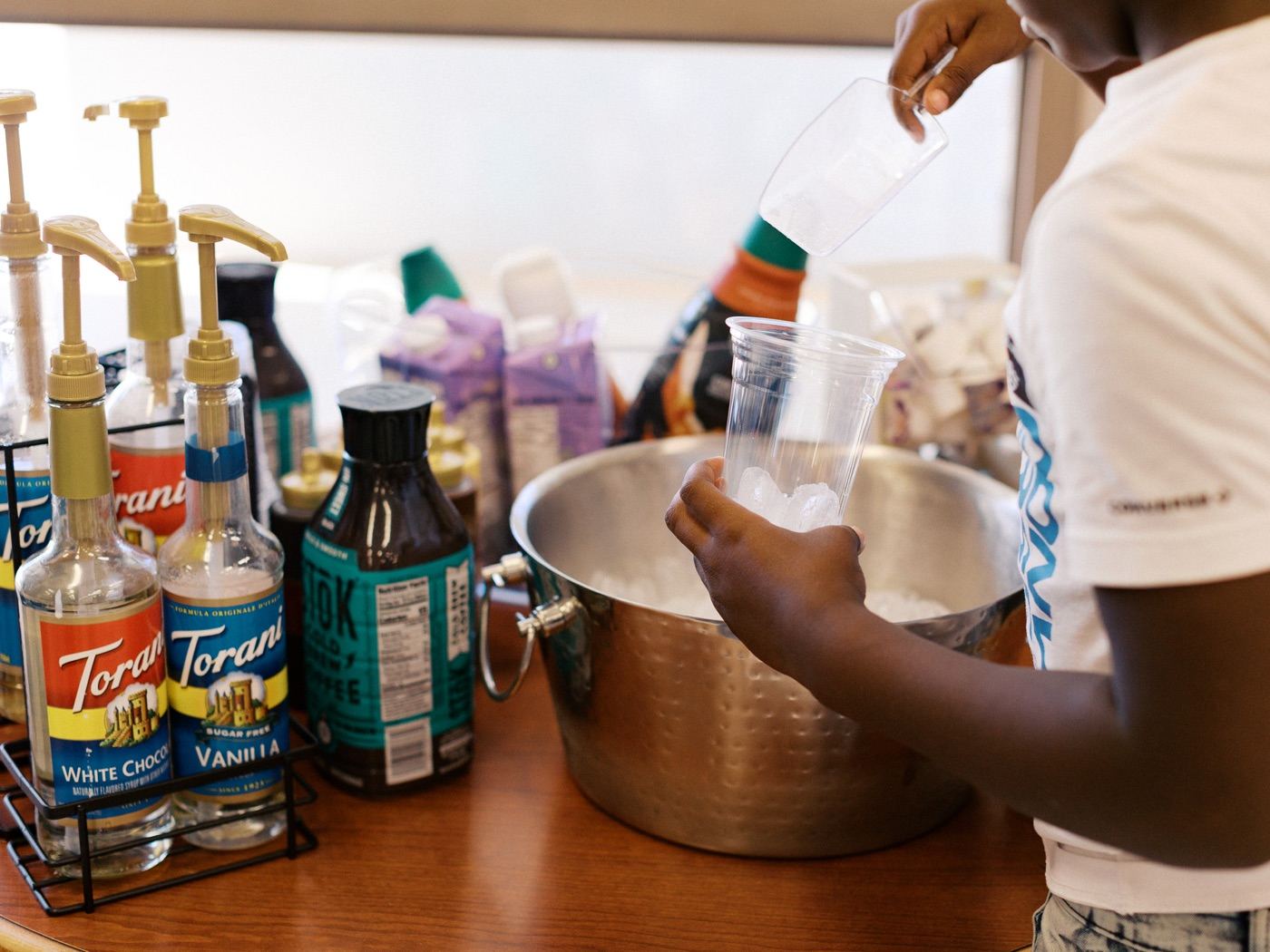Hands preparing iced coffee with Torani syrups at the church coffee bar
