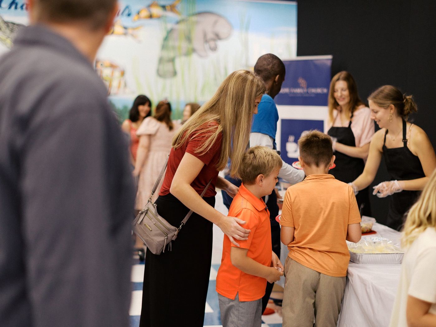 Mother with children at the food line during the church fellowship meal with volunteers serving