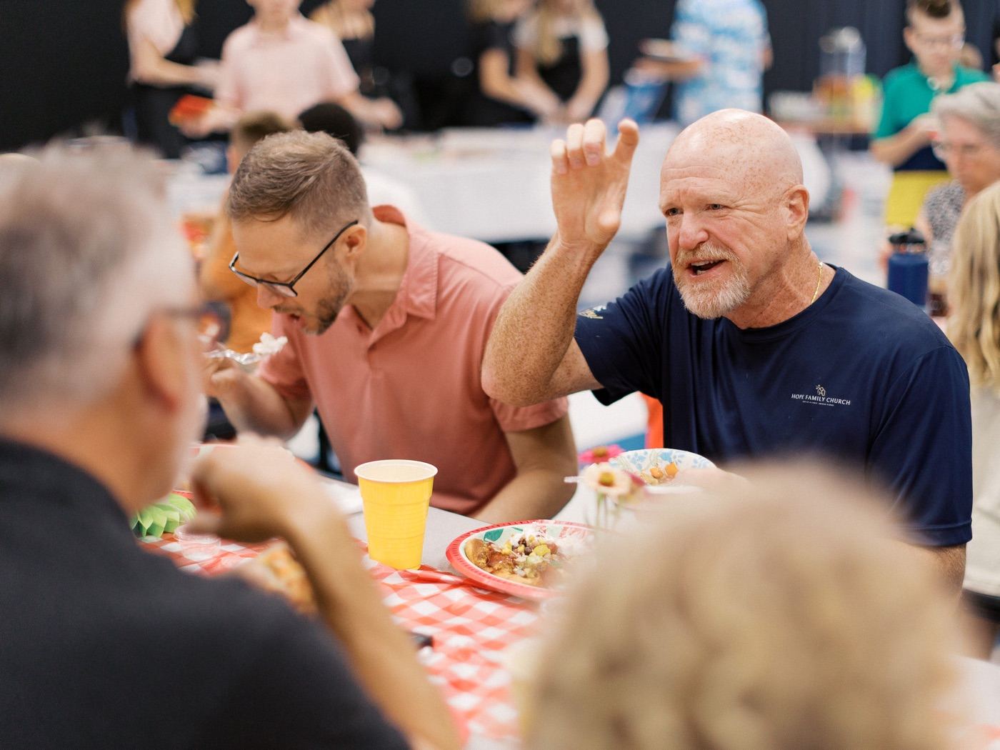 Group of men laughing and eating together at the Community Sunday meal
