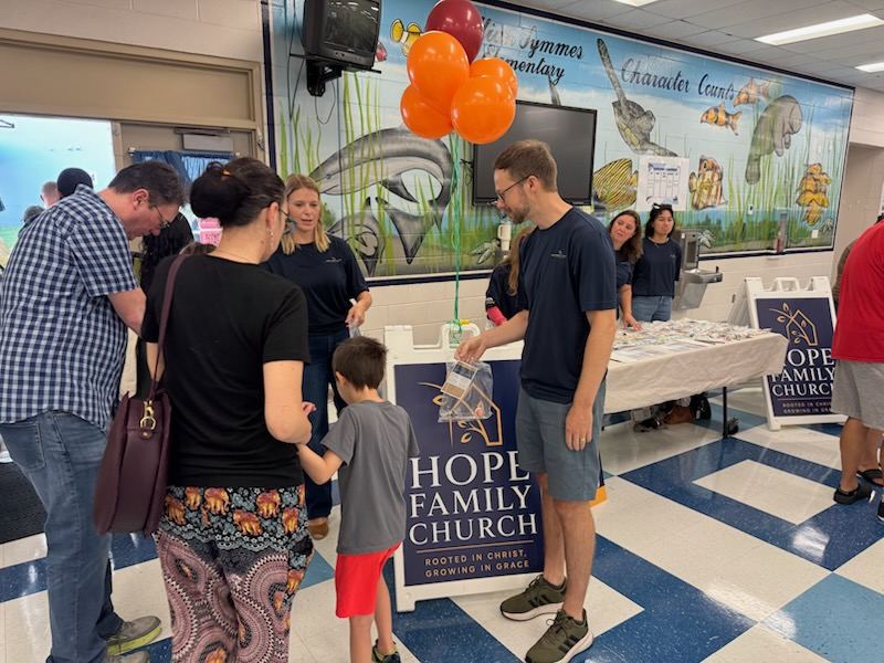 Hope Family Church volunteer handing a gift bag to a child at the Symmes Elementary school outreach event
