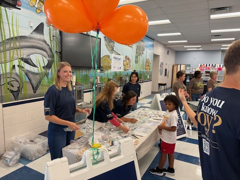 Hope Family Church volunteers smiling and assembling gift bags at the Symmes Elementary outreach table